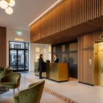 Boutique hotel lobby with Slatstone stone wall panels behind reception desk, featuring warm lighting and minimalist modern design.